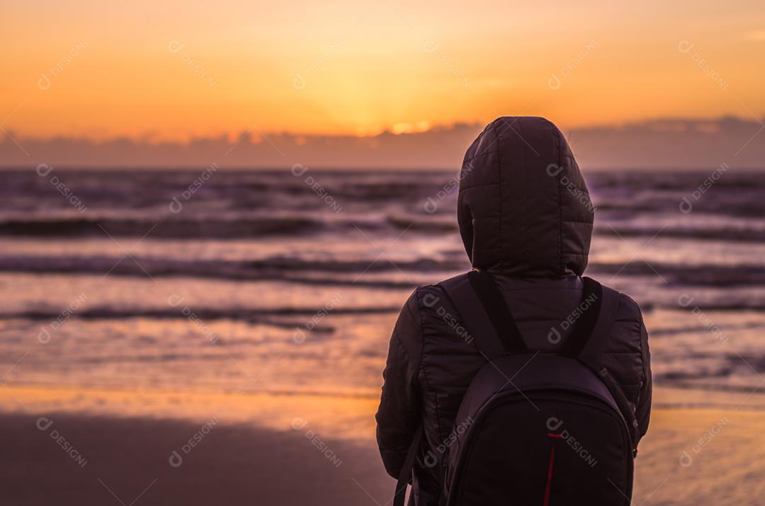 Mulher olhando para o horizonte, praia ao pôr do sol