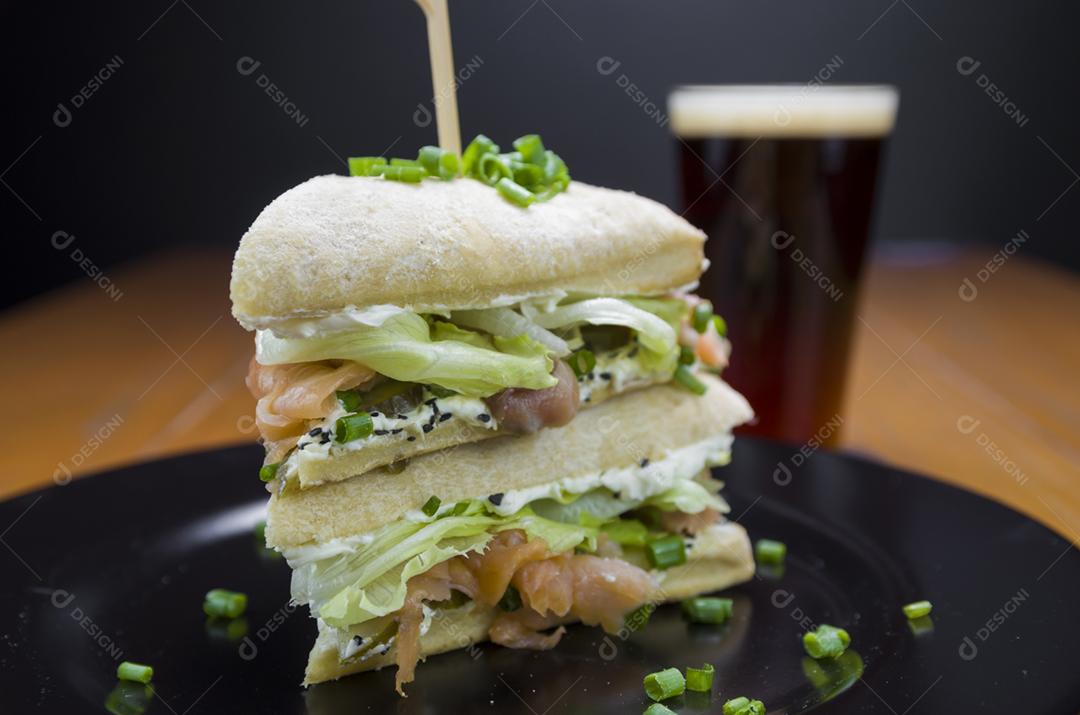 Delicioso sanduíche de salmão e copo de cerveja.