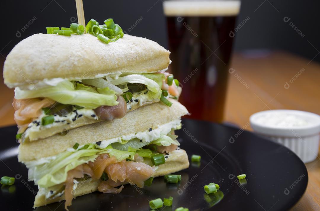 Delicioso sanduíche de salmão e copo de cerveja.