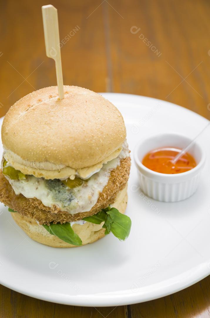 Hambúrguer de frango saboroso caseiro na mesa de madeira e fundo preto.