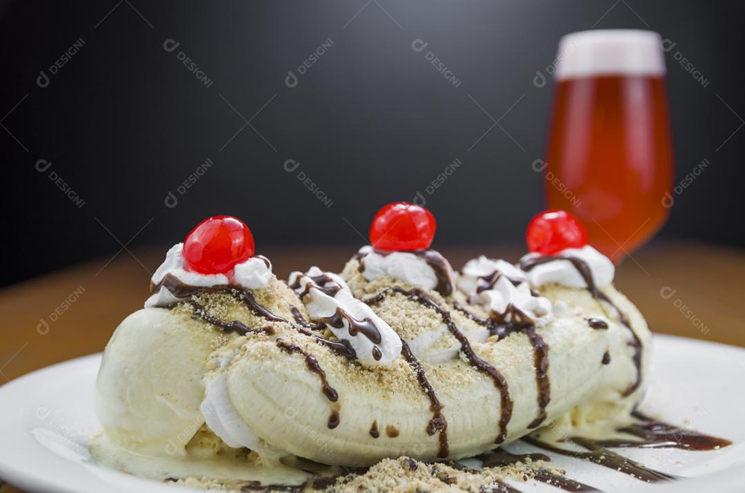 Deliciosa sobremesa de banana split e copo de cerveja de framboesa