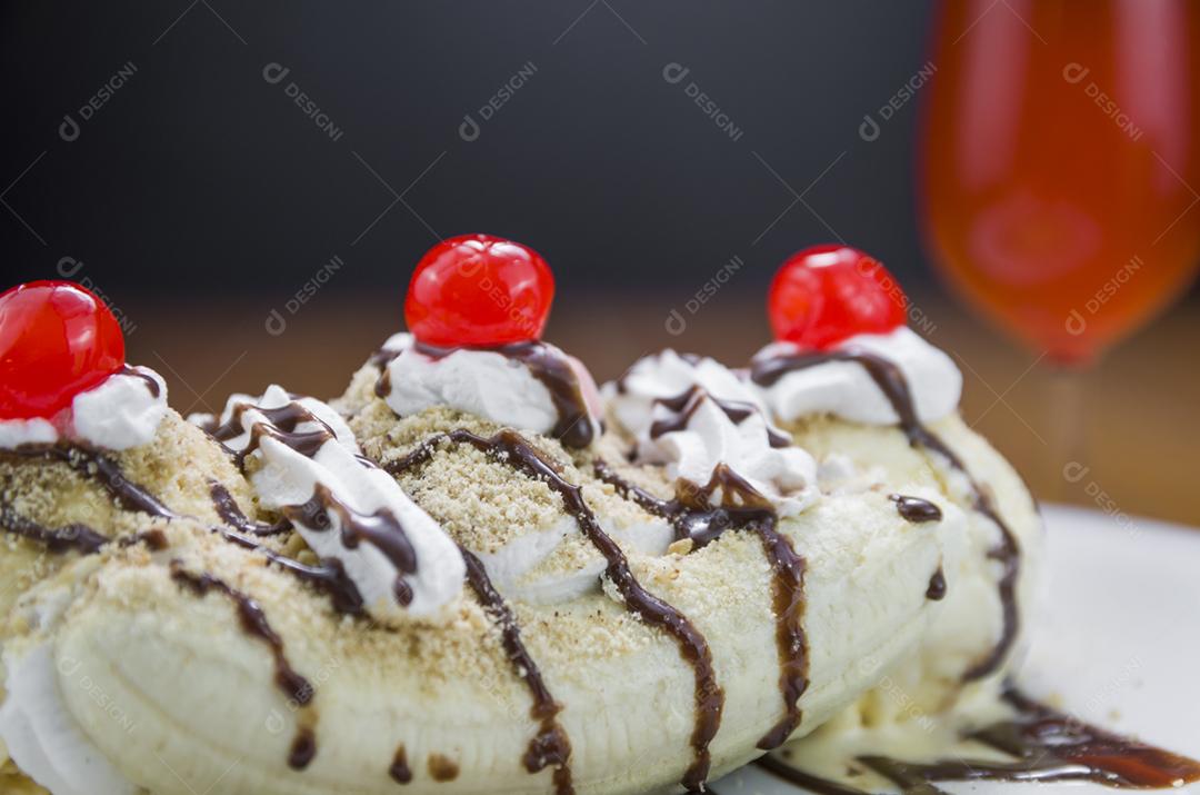 Deliciosa sobremesa de banana split e copo de cerveja de framboesa