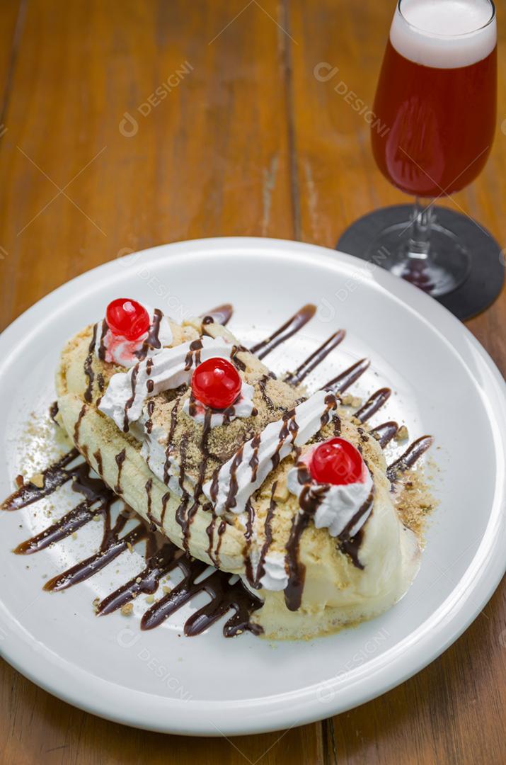 Deliciosa sobremesa de banana split e copo de cerveja de framboesa