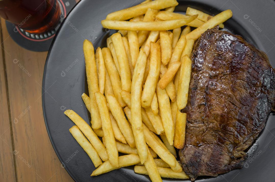 Delicioso prato de entrecosto grelhado com batatas fritas e copo de cerveja