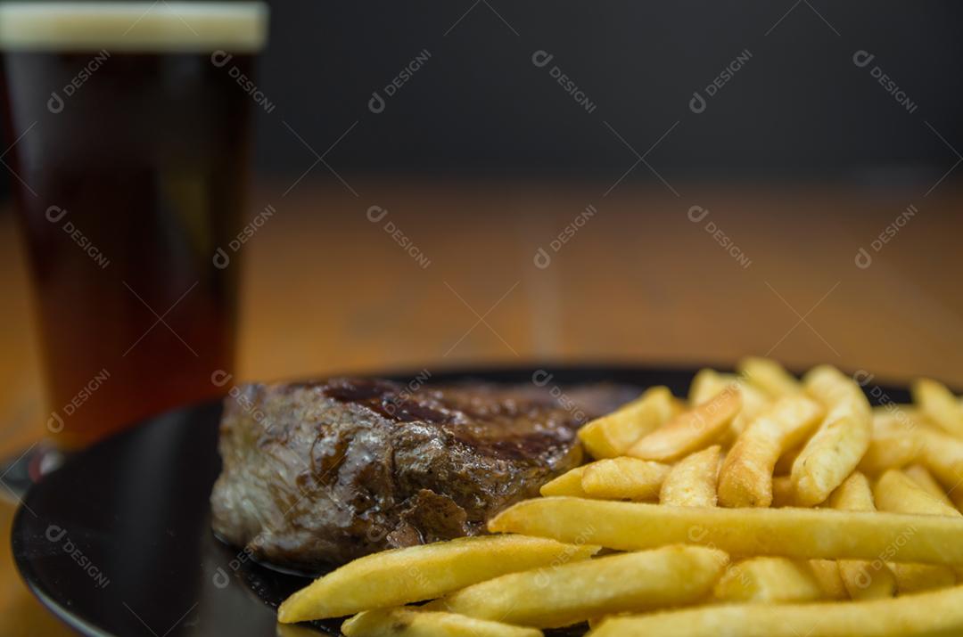 Delicioso prato de entrecosto grelhado com batatas fritas e copo de cerveja