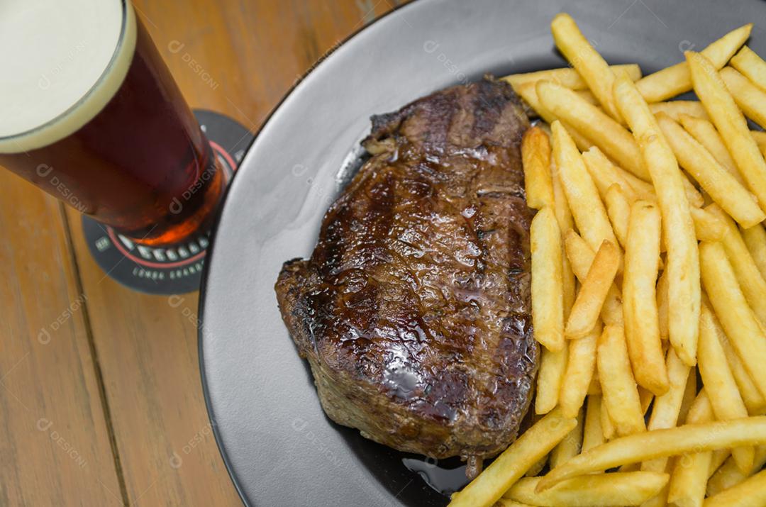 Delicioso prato de entrecosto grelhado com batatas fritas e copo de cerveja
