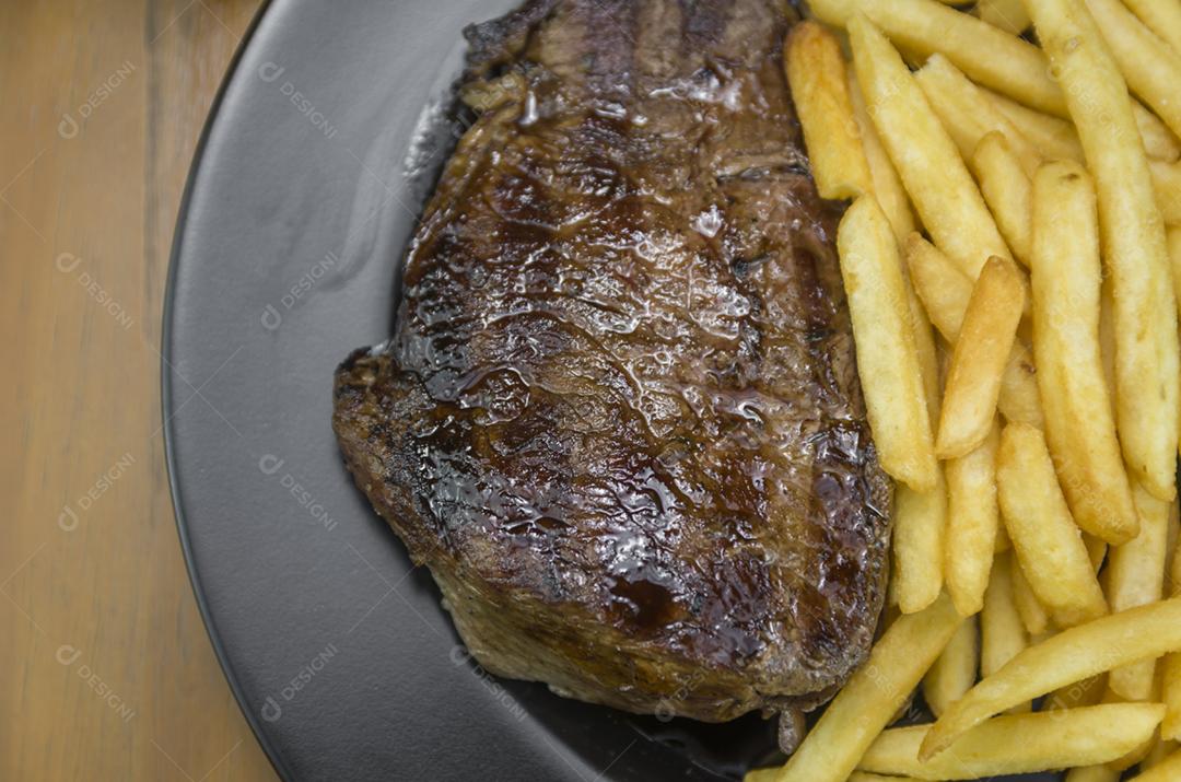 Delicioso prato de entrecosto grelhado com batatas fritas e copo de cerveja