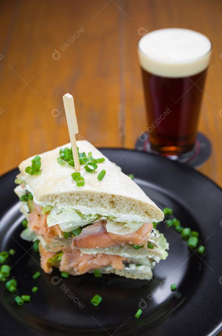 Delicioso sanduíche de salmão e copo de cerveja.