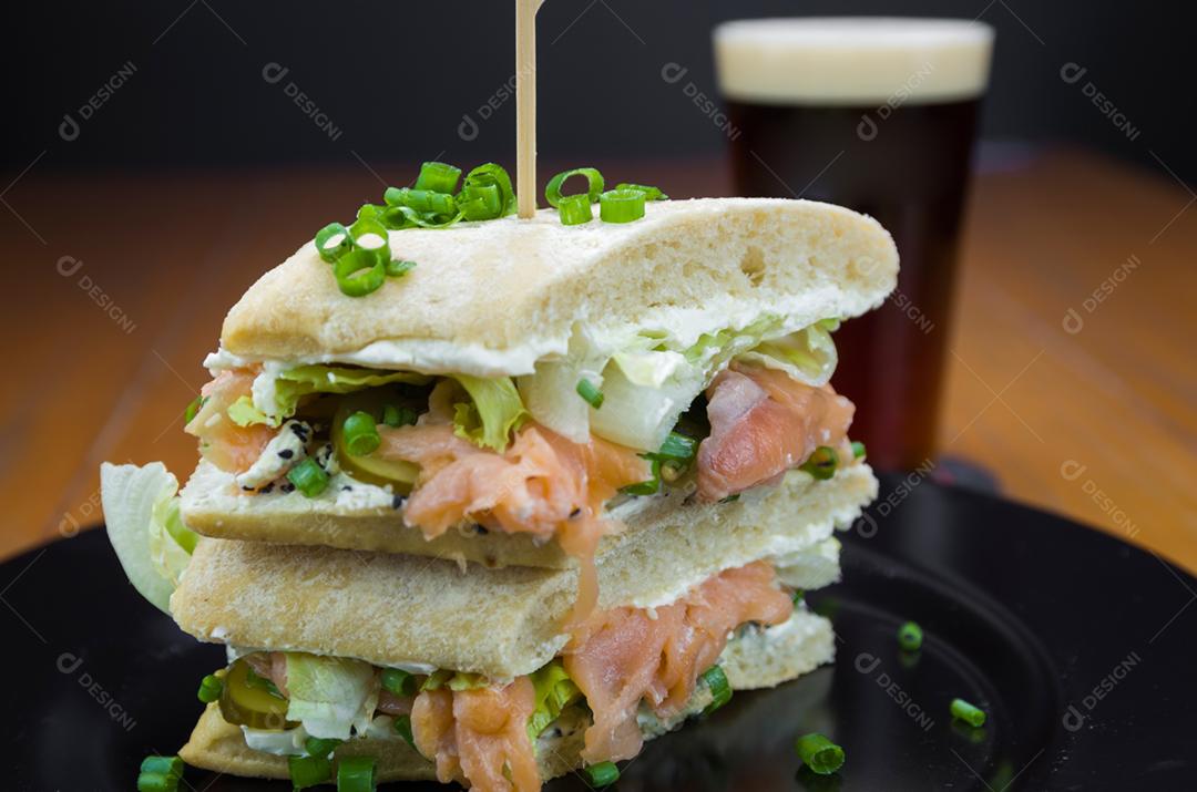 Delicioso sanduíche de salmão e copo de cerveja.