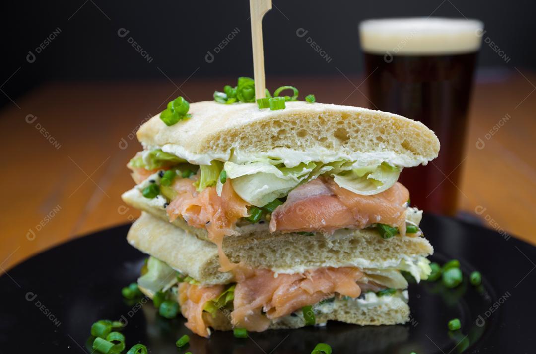 Delicioso sanduíche de salmão e copo de cerveja.