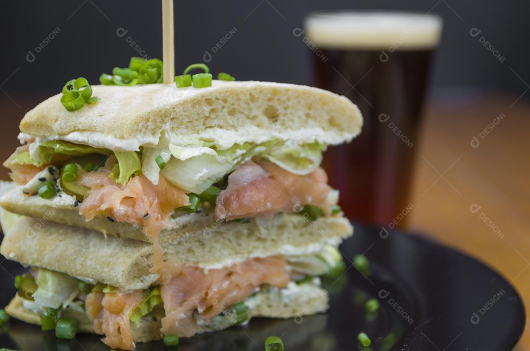 Delicioso sanduíche de salmão e copo de cerveja.