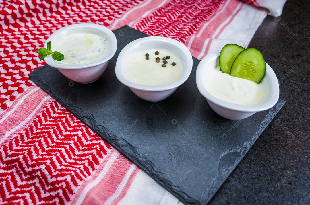 Deliciosa comida libanesa (árabe), thum, labneh e molhos tzatziki em fundo de pedra ardósia