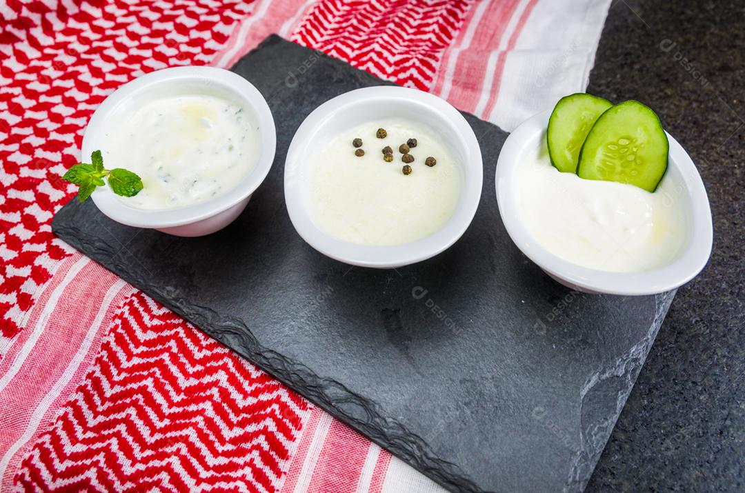 Deliciosa comida libanesa (árabe), thum, labneh e molhos tzatziki em fundo de pedra ardósia