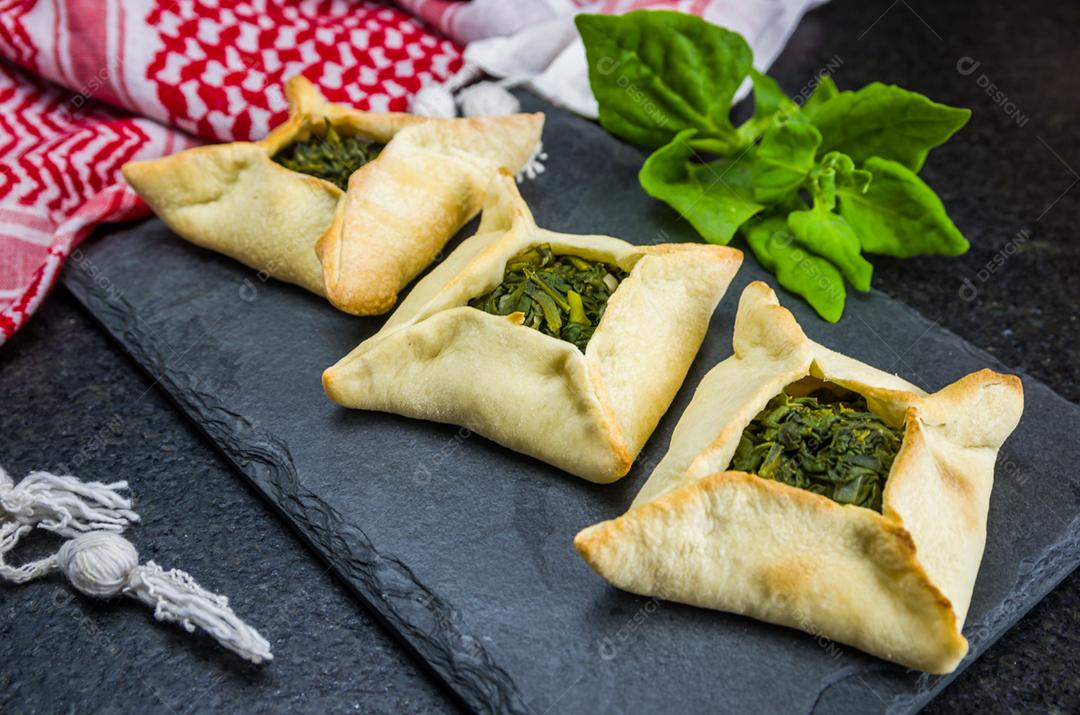 Deliciosa comida libanesa (árabe), esfiha de espinafre em fundo de pedra ardósia preta e turbante libanês