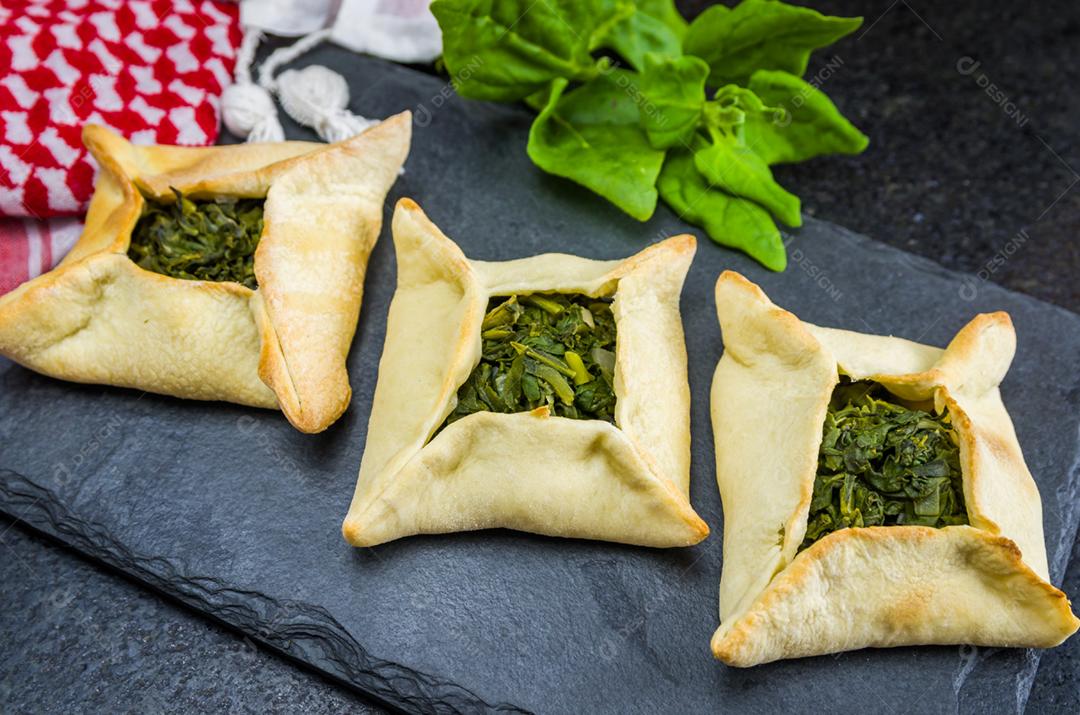 Deliciosa comida libanesa (árabe), esfiha de espinafre em fundo de pedra ardósia preta e turbante libanês