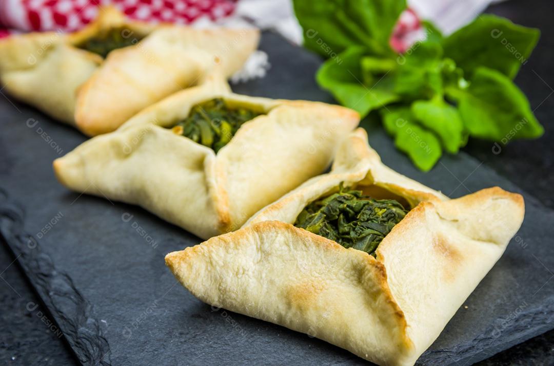 Deliciosa comida libanesa (árabe), esfiha de espinafre em fundo de pedra ardósia preta e turbante libanês