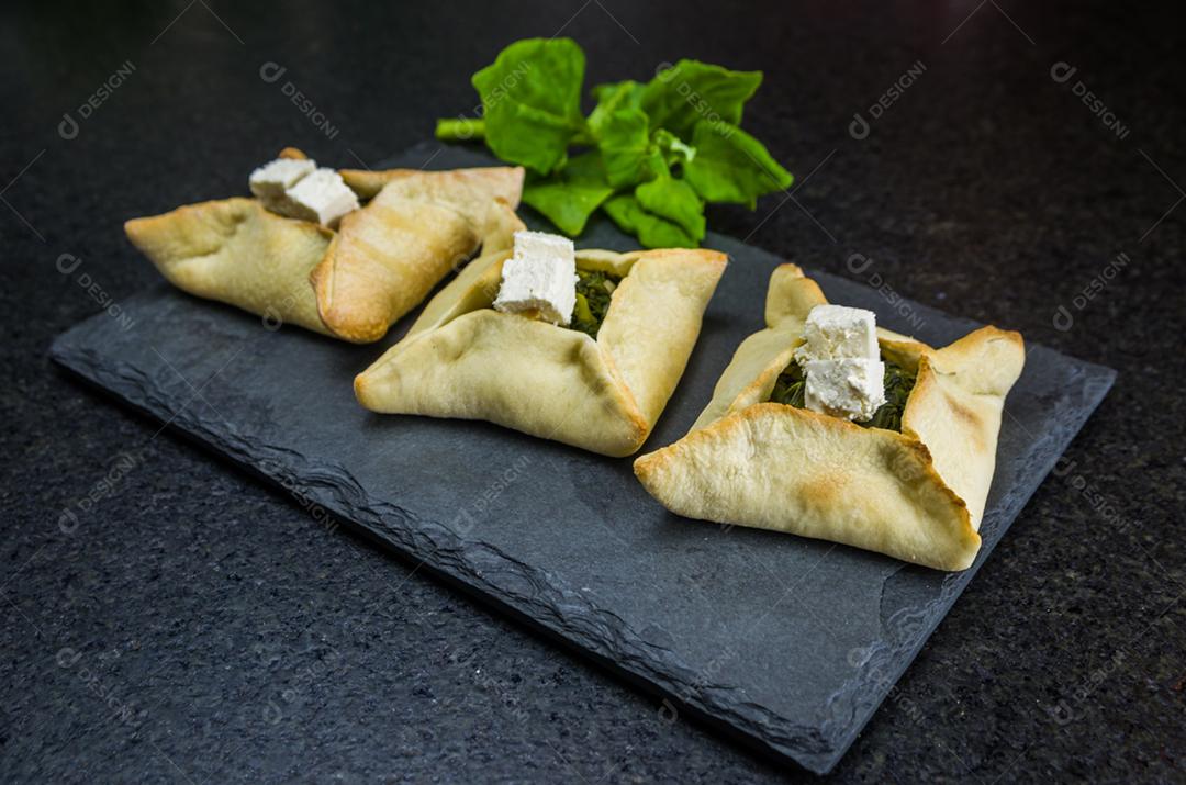 Deliciosa comida libanesa (árabe), esfiha de espinafre em fundo de pedra ardósia preta e turbante libanês