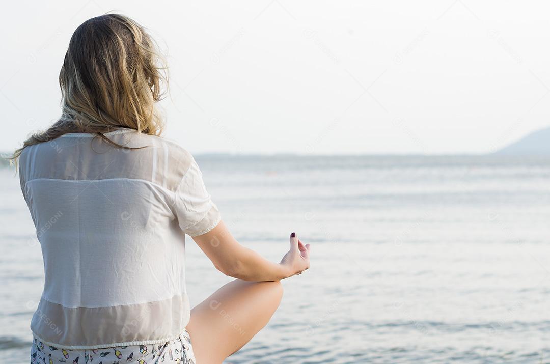A jovem pratica ioga e medita na posição de lótus o