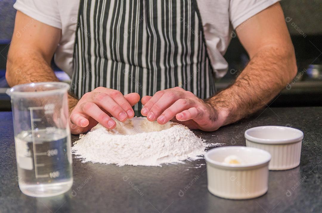 Homem preparando massa de pizza na mesa de granito preto
