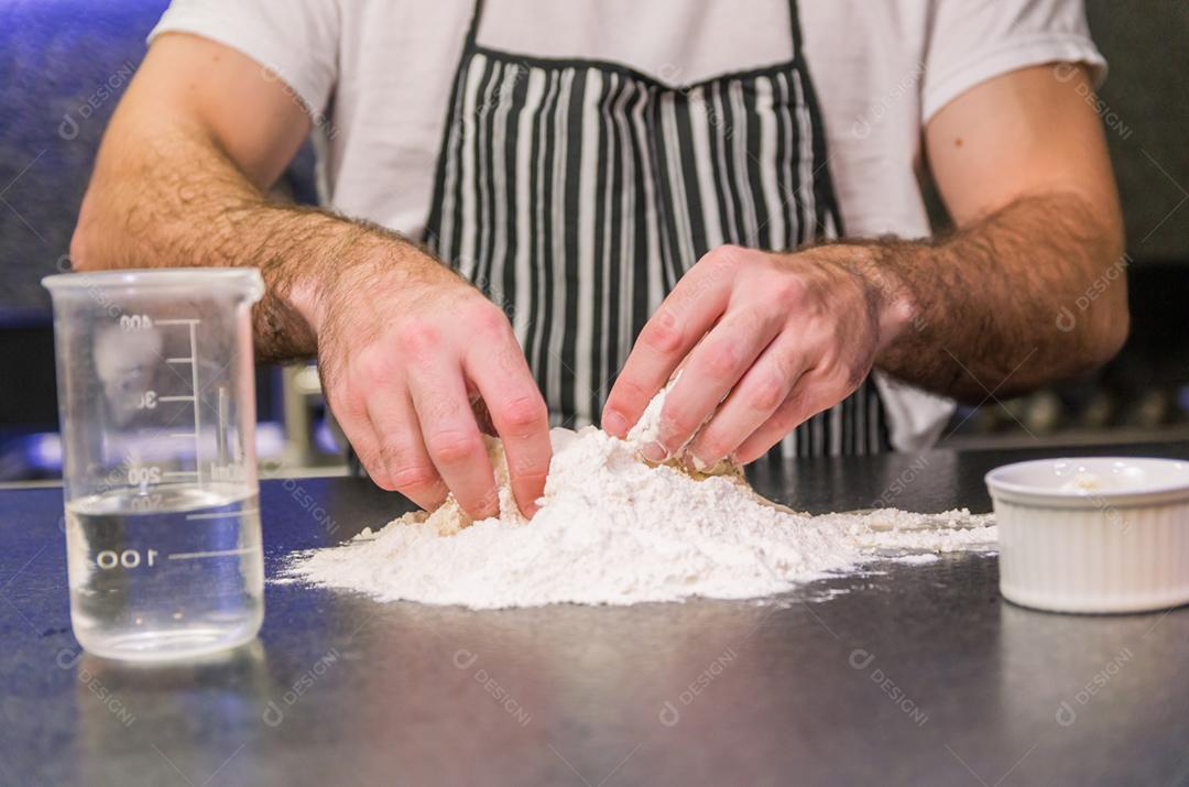 Homem preparando massa de pizza na mesa de granito preto