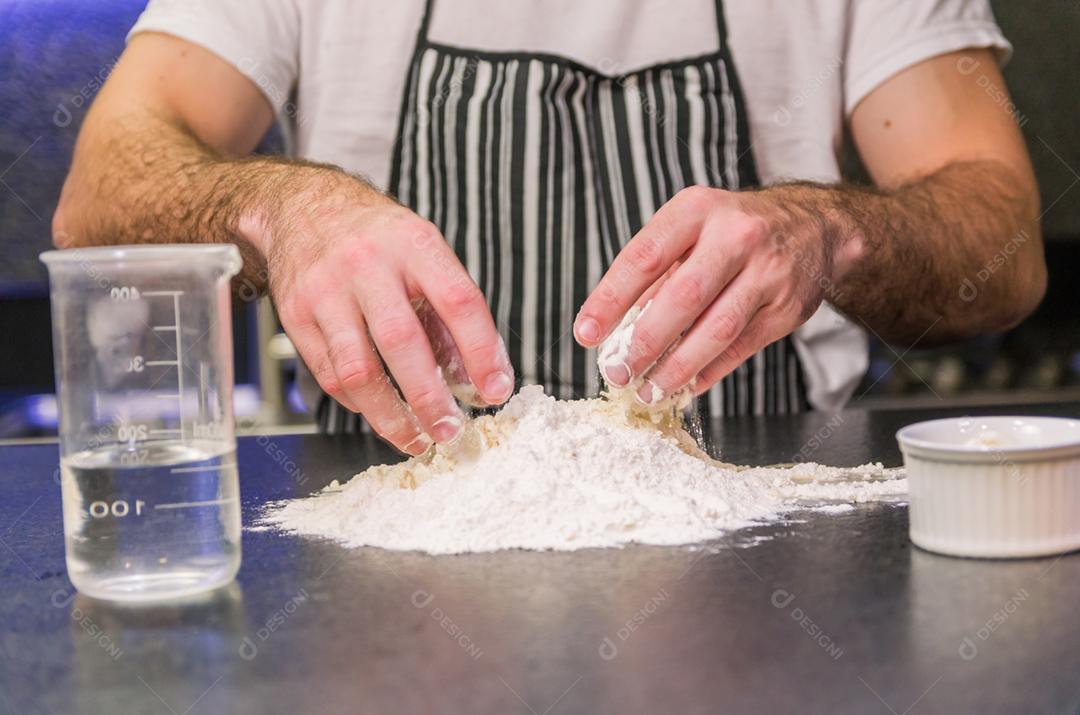 Homem preparando massa de pizza na mesa de granito preto