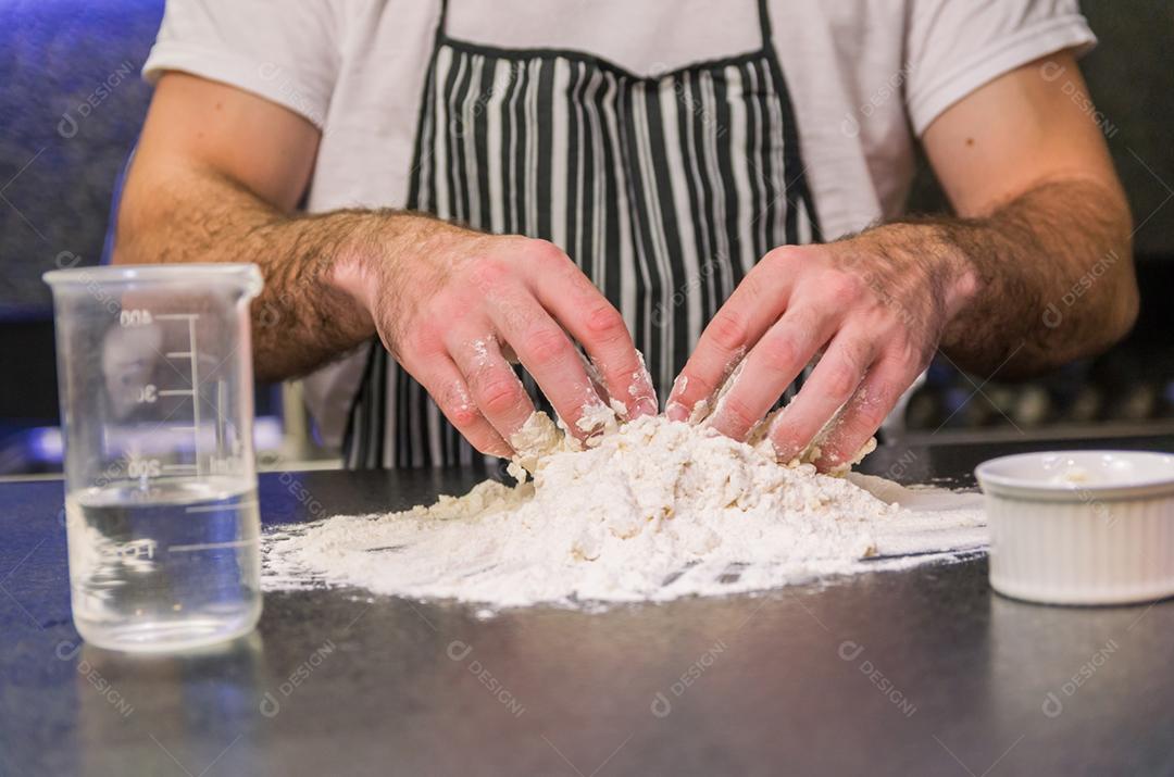 Homem preparando massa de pizza na mesa de granito preto