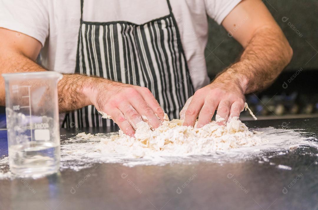 Homem preparando massa de pizza na mesa de granito preto