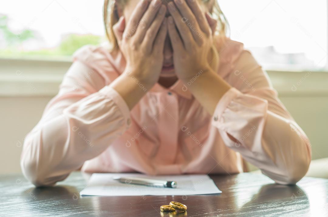 Grande conceito de divórcio, fim de relacionamento, jovem triste, assinando acordo de divórcio, com as mãos no rosto.