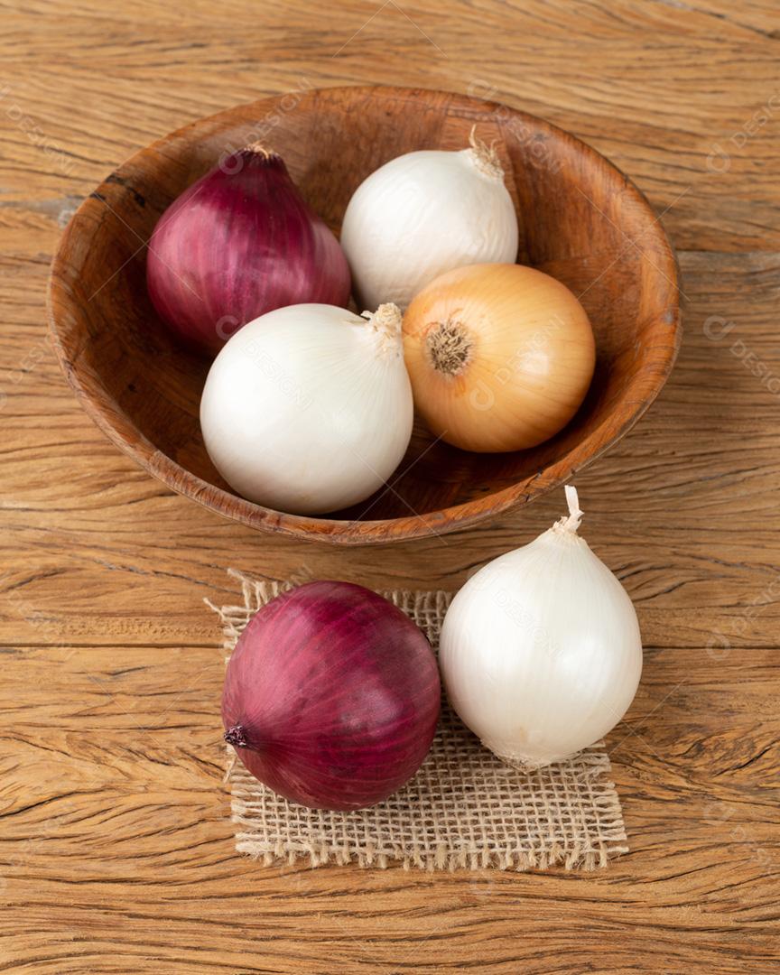 Cebolas variadas em uma tigela sobre a mesa de madeira