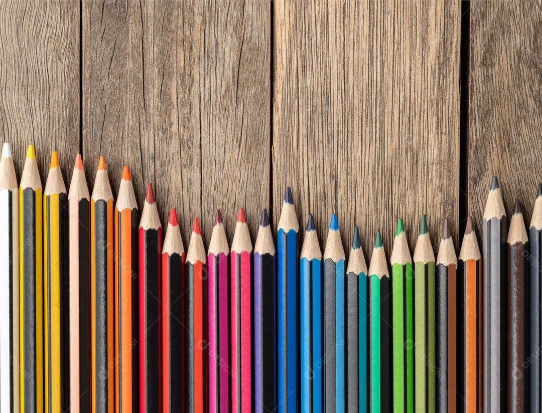 Lápis de cores sortidas sobre mesa de madeira com espaço de cópia