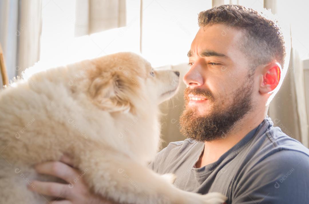 Homem brincando com seu cachorro Spitz alemão de cor amarela clara
