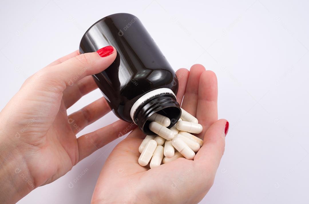 Mão de mulher virando frasco de remédio na palma da mão. Prescrição do médico.