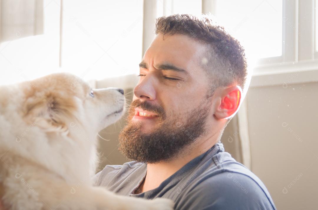 Homem brincando com seu cachorro Spitz alemão de cor amarela clara