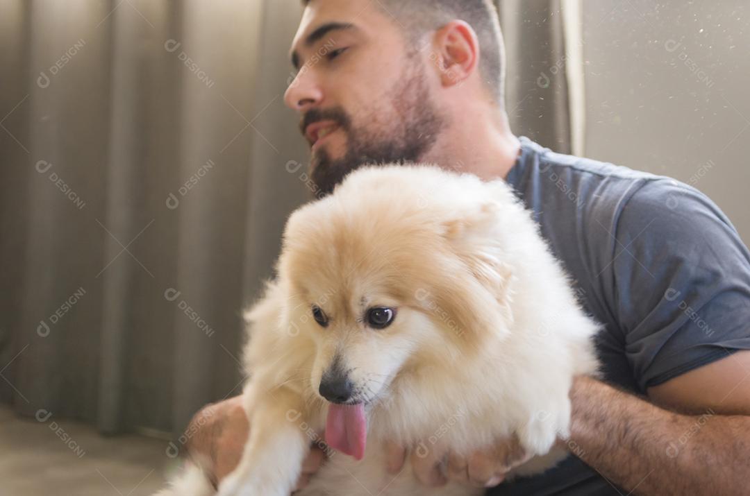 Homem brincando com seu cachorro Spitz alemão de cor amarela clara