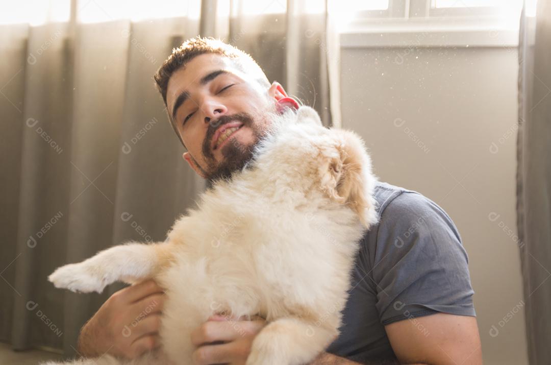 Homem brincando com seu cachorro Spitz alemão de cor amarela clara