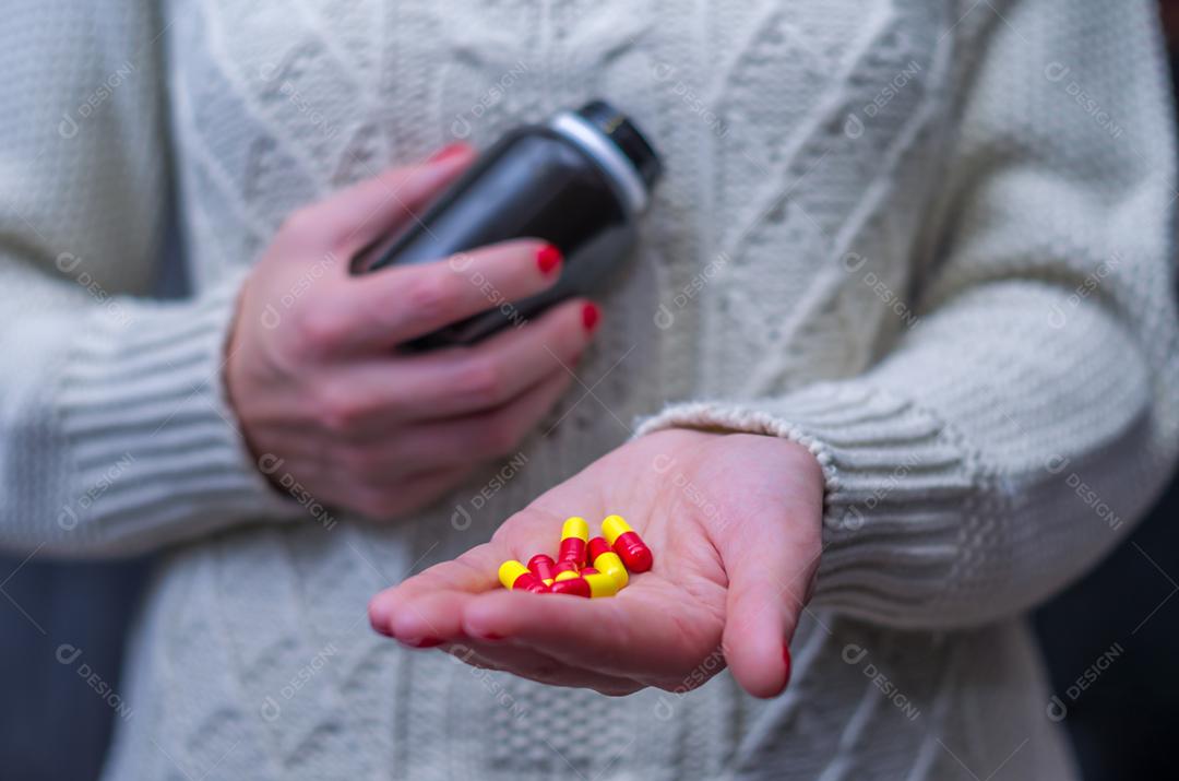 Mulher vestida com roupas de inverno com pílulas de medicamentos. pílulas na mão mulher com gripe