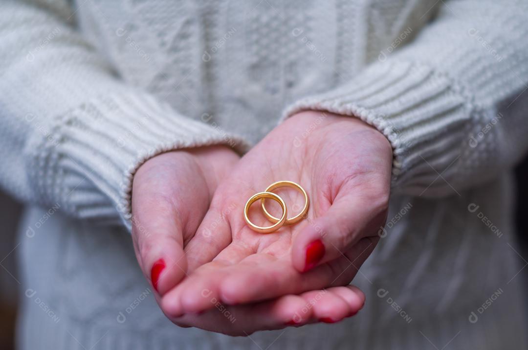 Grande conceito de mão de mulher de divórcio com duas alianças de casamento de ouro na mão.