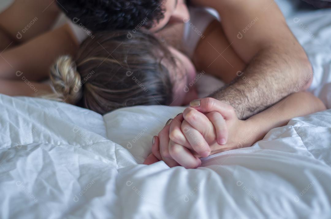 Jovem casal fazendo amor na cama foco na mão