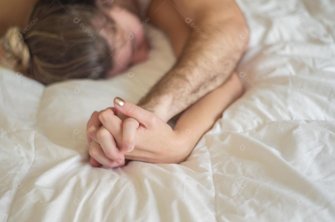 Jovem casal fazendo amor na cama foco na mão