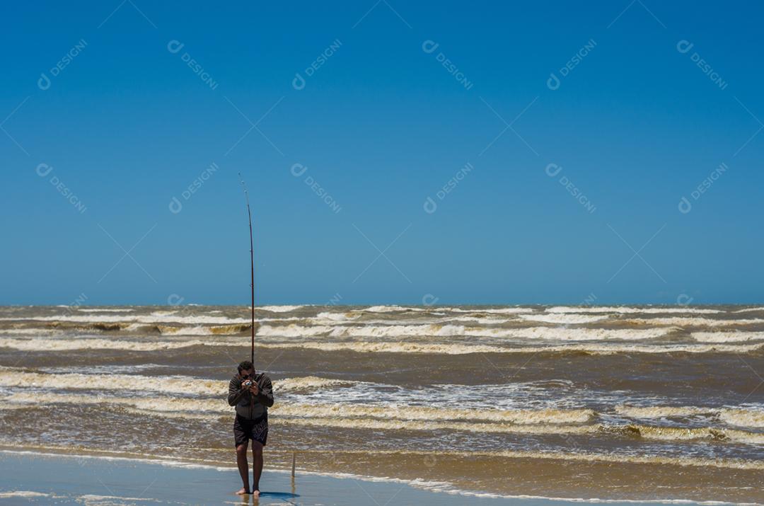 Jovem pesca na praia, pesca esportiva.