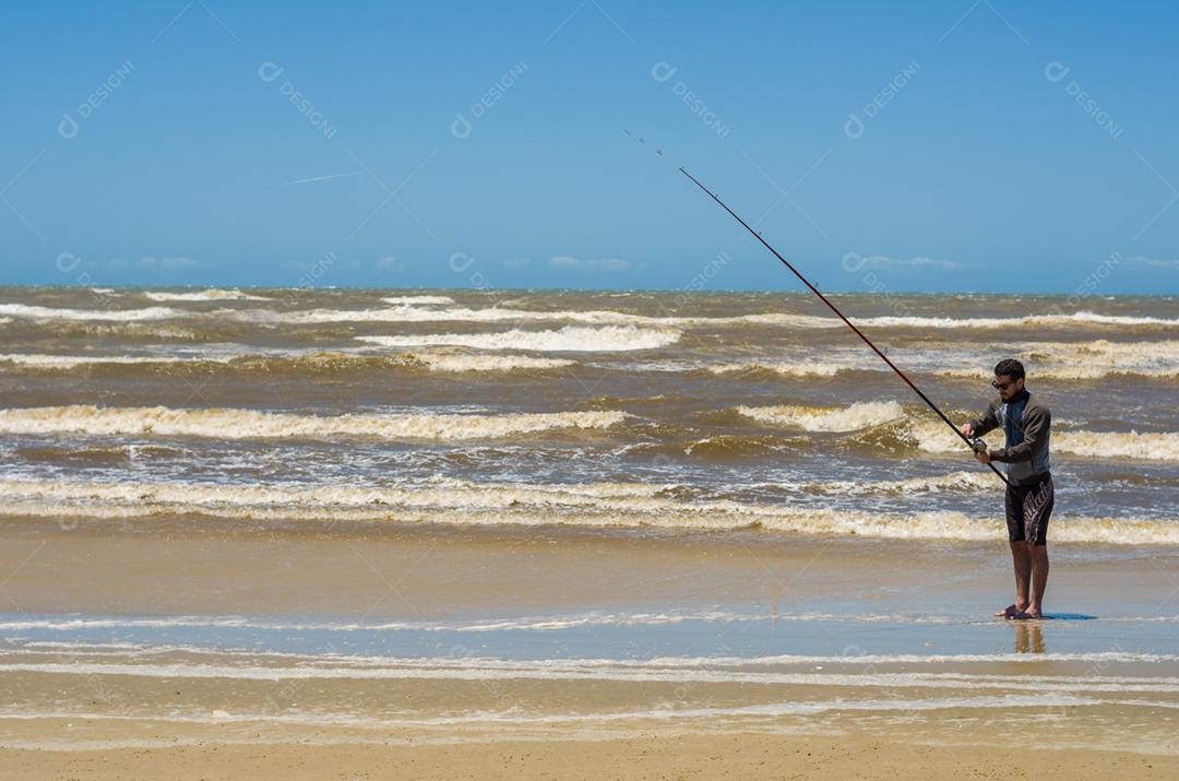 Jovem pesca na praia, pesca esportiva.