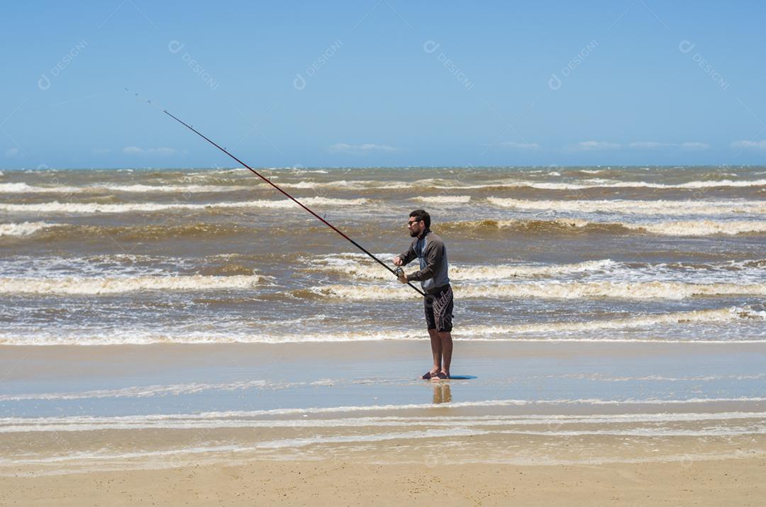 Jovem pesca na praia, pesca esportiva.