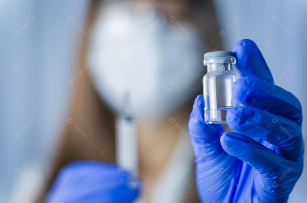 Médica com estetoscópio no ombro segurando seringa e vacina COVID-19. Conceito de saúde e médico.