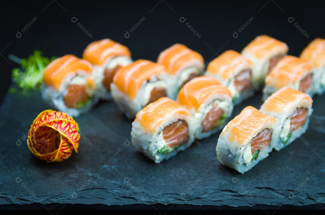 Sushi, cozinha tradicional japonesa. Delicioso Uramaki na placa decorada, fundo preto.