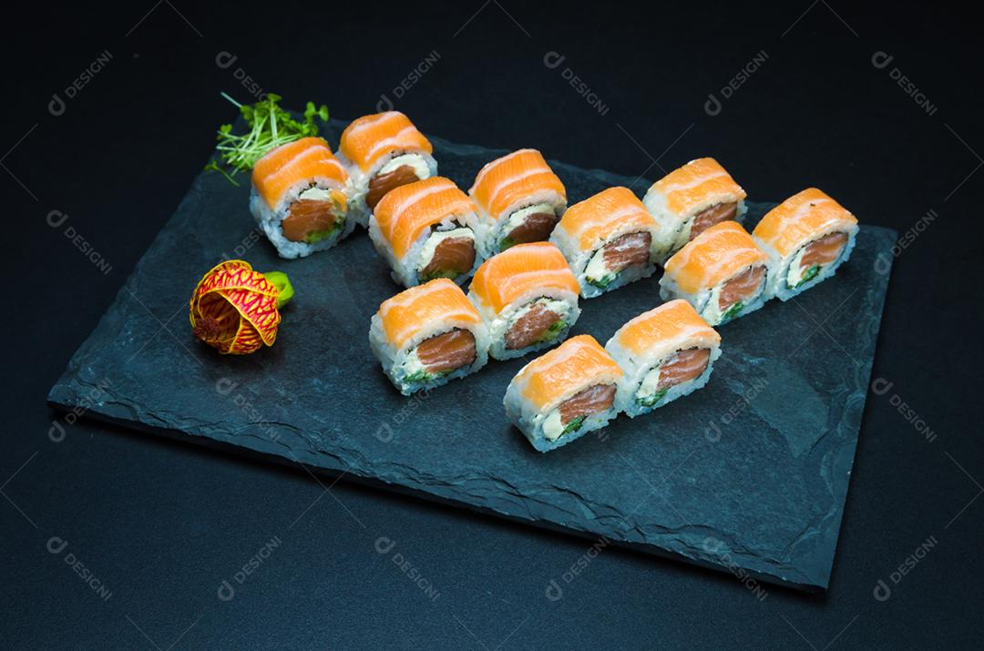 Sushi, cozinha tradicional japonesa. Delicioso Uramaki na placa decorada, fundo preto.