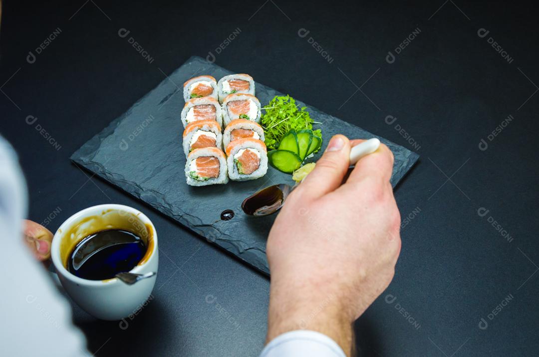 Sushiman adicionando o molho de tara ao prato. Sushi, cozinha tradicional japonesa. Delicioso Uramaki