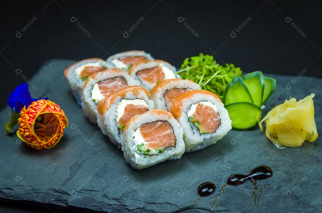 Sushi, cozinha tradicional japonesa. Delicioso Uramaki na placa decorada, fundo preto.