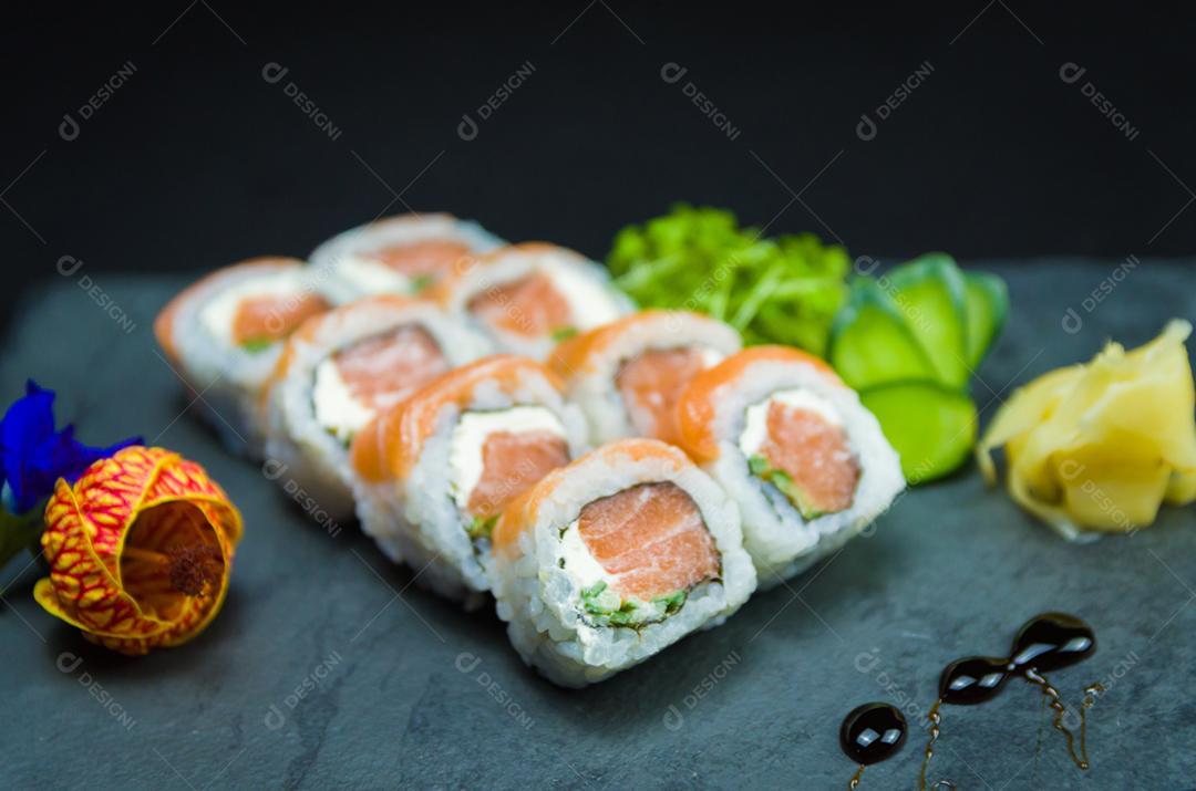 Sushi, cozinha tradicional japonesa. Delicioso Uramaki na placa decorada, fundo preto.