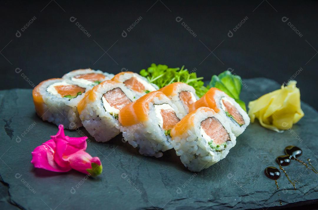 Sushi, cozinha tradicional japonesa. Delicioso Uramaki na placa decorada, fundo preto.