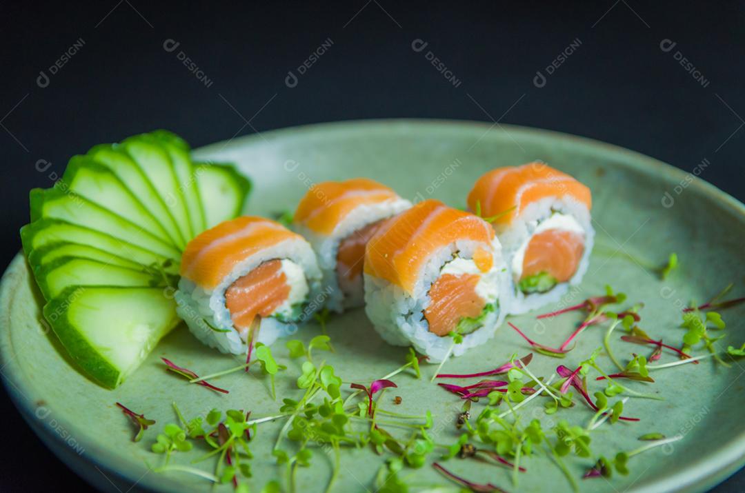 Sushi, cozinha tradicional japonesa. Delicioso Uramaki na placa decorada, fundo preto.